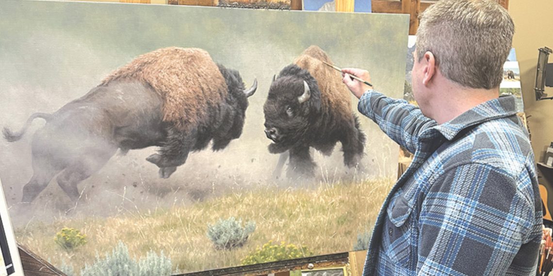 Wildlife artist Kyle Sims applies finishing touches to a large oil painting of two bull bison fighting in his studio.
