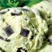 Close up of mint chocolate chip ice cream with large dark chocolate chunks in creamy pale green scoops.