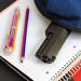 A handgun partially visible inside an unzipped backpack rests on top of school notebooks, illustrating a school safety concern.