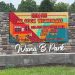A stone entrance sign at Wana B Park displays a digital message promoting the park's "No Cook Wednesdays" event.