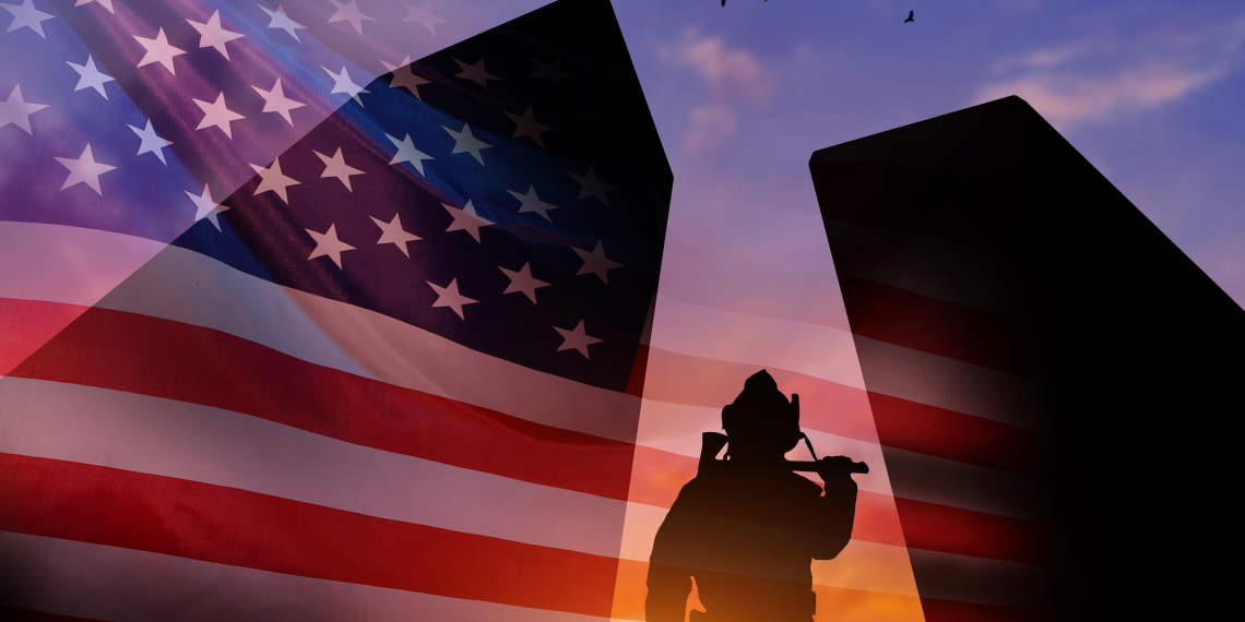 Silhouetted soldier in a spotlight in front of an American flag at sunset with birds in the sky.