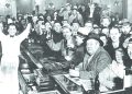 A crowd of men in a historic bar raise bottles and glasses in celebration after Prohibition ended.