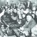 A crowd of men in a historic bar raise bottles and glasses in celebration after Prohibition ended.