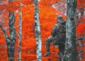 A hunter in camouflage sits in a tree stand among orange autumn leaves.