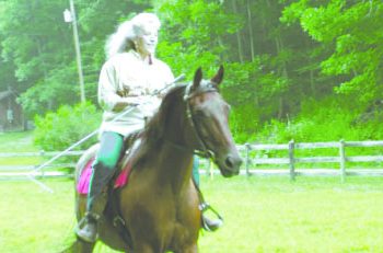 Shelly Brown rides a horse through a fenced pasture on her West Virginia farm.