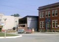 Historic photo of the original Ross Theater being demolished in Carmichaels, with the newer Lund Theater visible behind it and the First National Bank building at right.