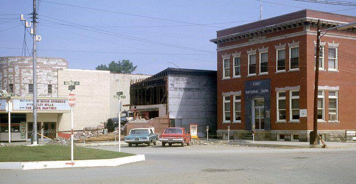 Historic photo of the original Ross Theater being demolished in Carmichaels, with the newer Lund Theater visible behind it and the First National Bank building at right.