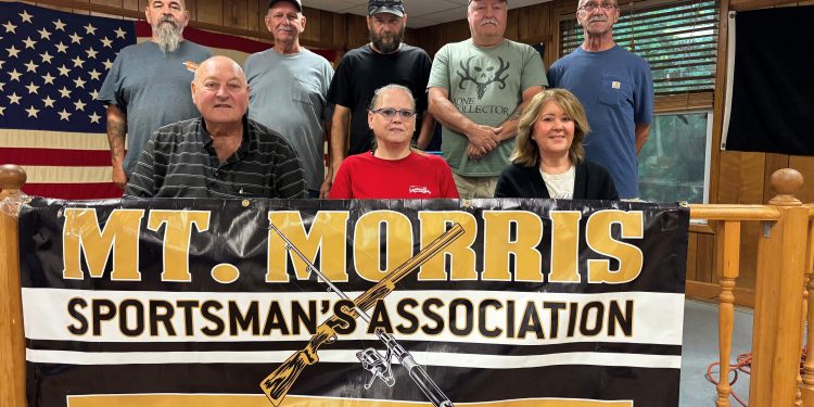 Members of the Mount Morris Sportsman’s Association pose behind a banner celebrating the club’s 75th anniversary.