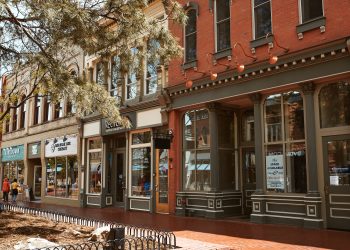 Historic small-town Main Street with restored brick storefronts, local businesses, and tree-lined sidewalks.