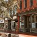 Historic small-town Main Street with restored brick storefronts, local businesses, and tree-lined sidewalks.