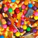 An assortment of colorful Halloween candies, including candy corn, gummy worms, lollipops, and round fruit-flavored candies.