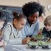 A teacher helps three young students examine seedlings during a hands-on classroom activity.