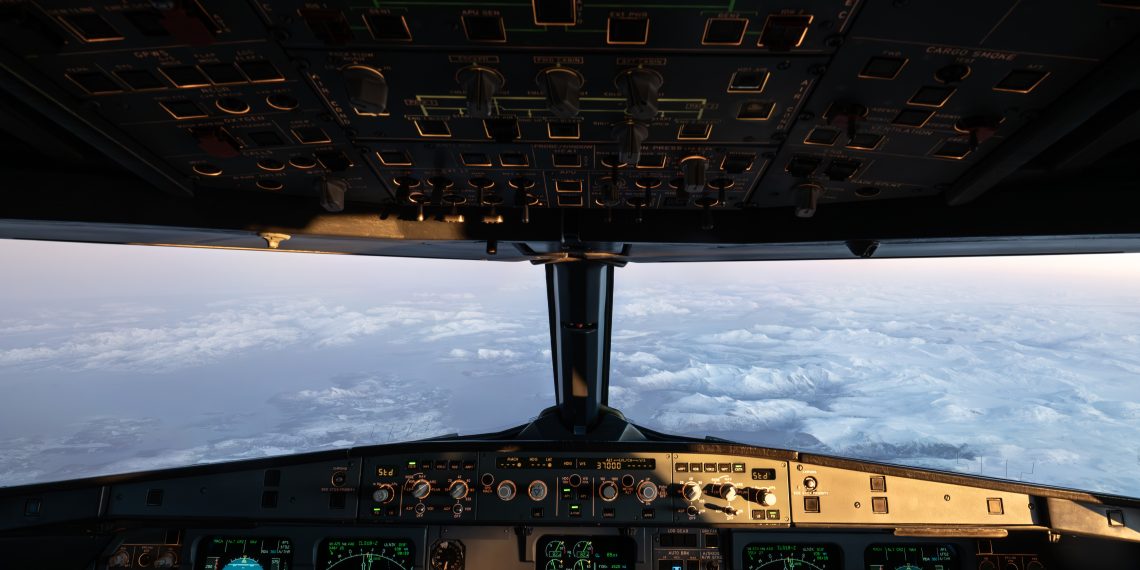 Airplane cockpit instruments and overhead controls with clouds and a snowy landscape visible through the windshield.