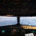 Airplane cockpit instruments and overhead controls with clouds and a snowy landscape visible through the windshield.