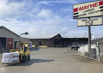 A forklift transports building materials outside Wayne Lumber & Supply in Waynesburg, Pennsylvania, with lumberyard buildings and a large Wayne Lumber Home Center sign visible.