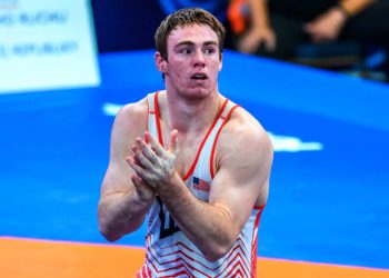 U20 World Wrestling Champion Michael Boyle claps his hands while wearing a red and white USA wrestling singlet on a competition mat.