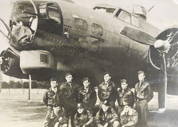 A black-and-white World War II photograph shows Hershel “Ted” Bowers and fellow American airmen posing in front of their B-17 Flying Fortress bomber, the Jub Jub Bird.