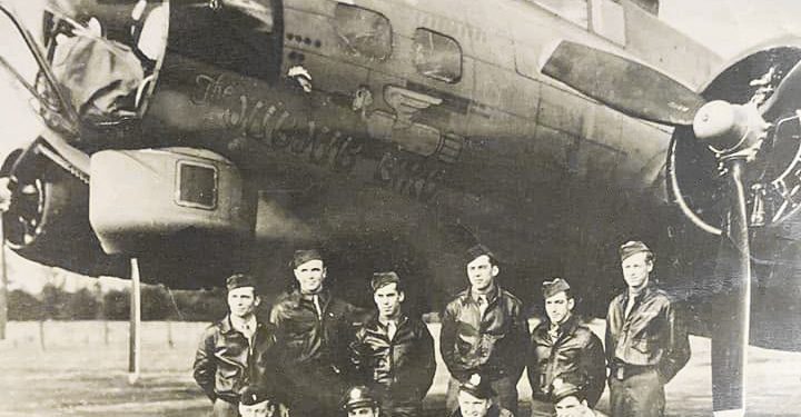 A black-and-white World War II photograph shows Hershel “Ted” Bowers and fellow American airmen posing in front of their B-17 Flying Fortress bomber, the Jub Jub Bird.