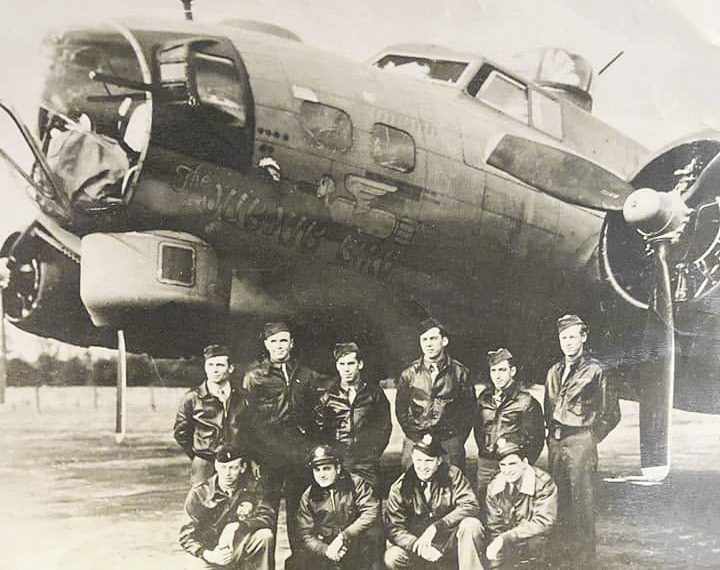 A black-and-white World War II photograph shows Hershel “Ted” Bowers and fellow American airmen posing in front of their B-17 Flying Fortress bomber, the Jub Jub Bird.