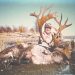 Hunter Larry Goehring poses behind a harvested bull caribou with massive antlers in a remote wilderness landscape near a body of water.
