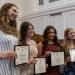 Four smiling Waynesburg University students pose together while holding framed Alpha Lambda Delta honor society certificates.