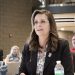 Pennsylvania State Senator Camera Bartolotta, wearing a dark blazer and patterned blouse, speaks into a microphone during a public hearing with attendees in the background.
