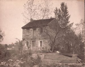 Historic photograph of Captain James Seals' two-story stone house in West Waynesburg, featuring stone walls, wooden doors, and surrounding trees.