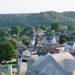 A panoramic view of Waynesburg, Pennsylvania, featuring residential homes, lush green hills, and cemetery headstones in the foreground.
