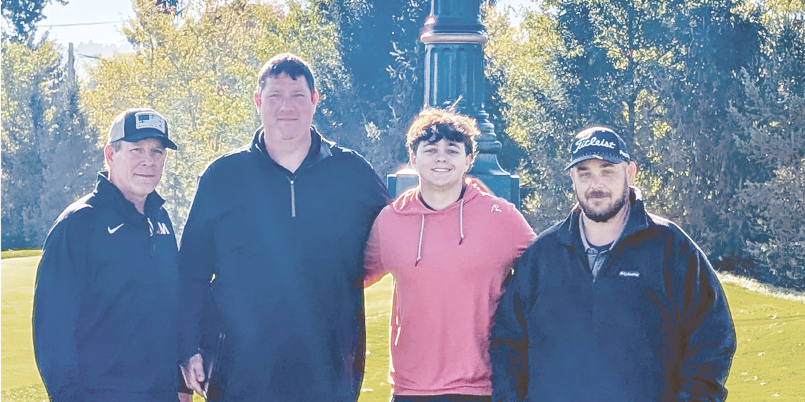 Jefferson-Morgan senior golfer Miles Sowden stands with three supporters beneath the large Oakmont Country Club Rolex clock on a sunny day.